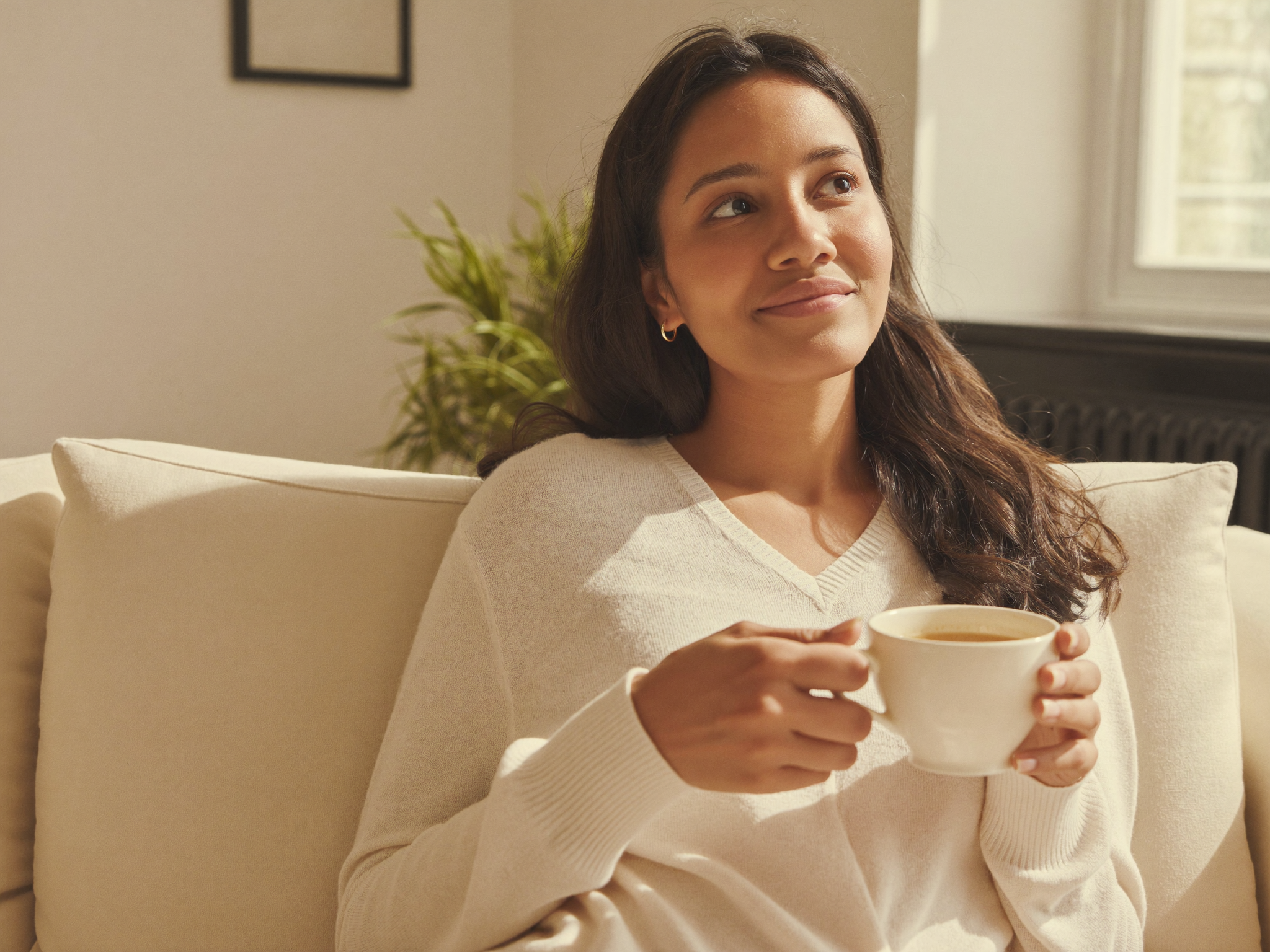 A woman relaxing calmly at home with a warm drink