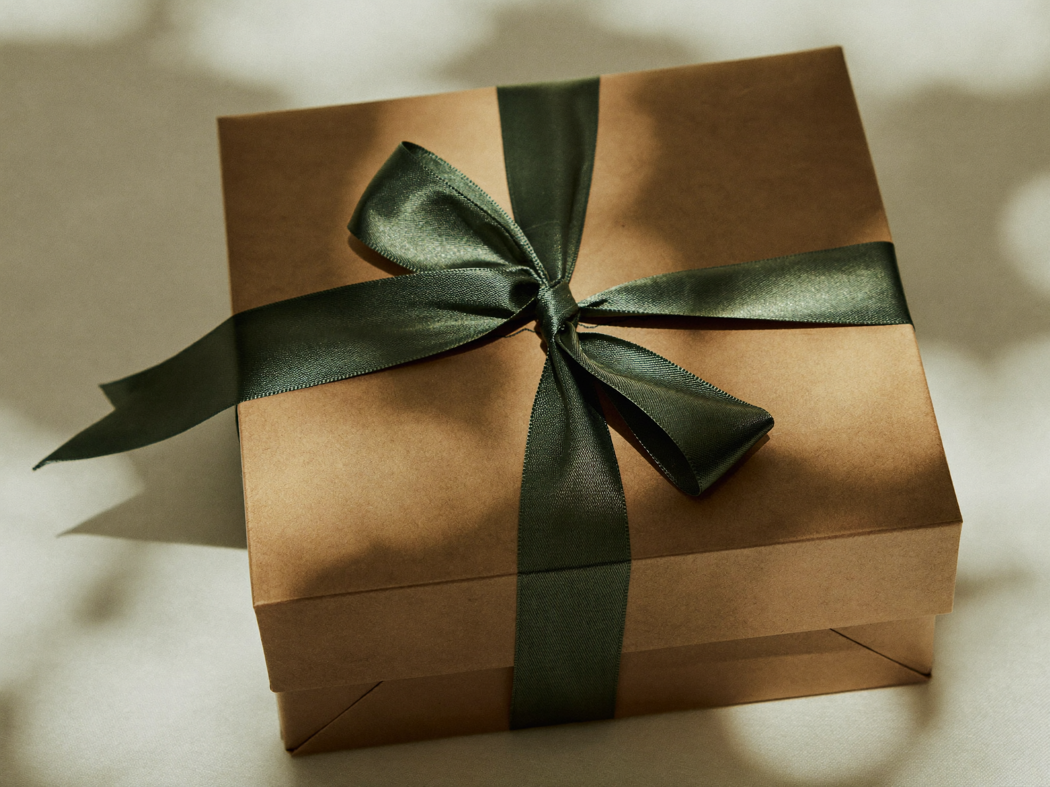 A kraft paper gift box tied with a deep green ribbon