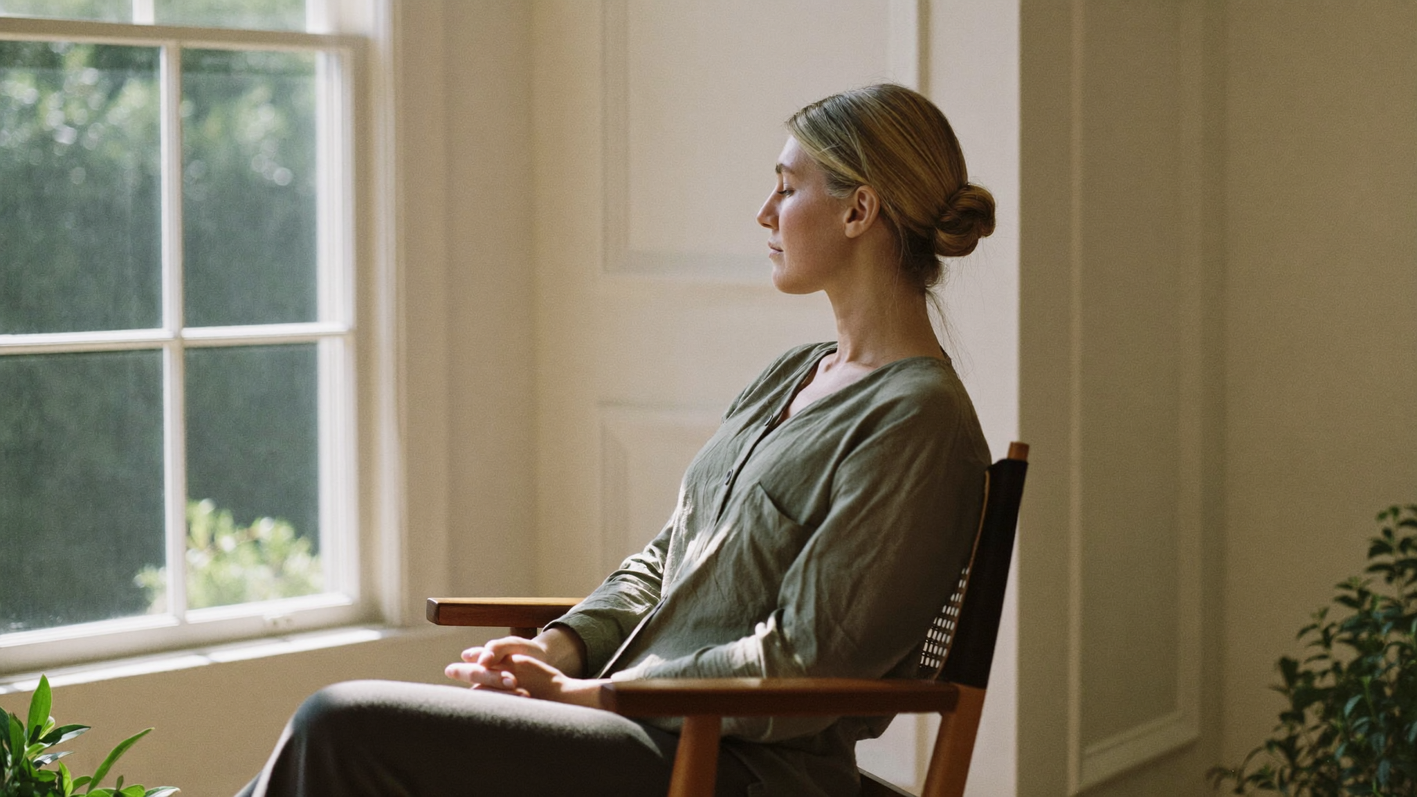 A woman sitting calmly in sunlight by a window